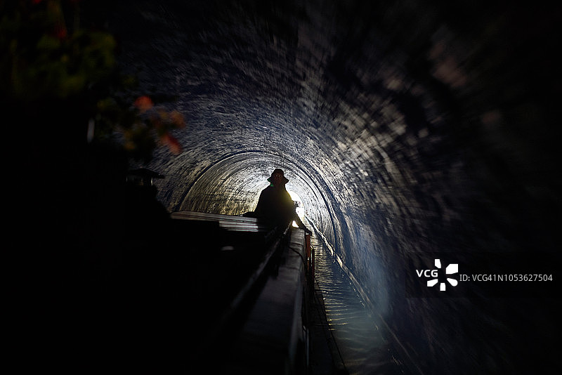 女人驾驶运河船穿过伦敦市中心摄政运河上的隧道图片素材