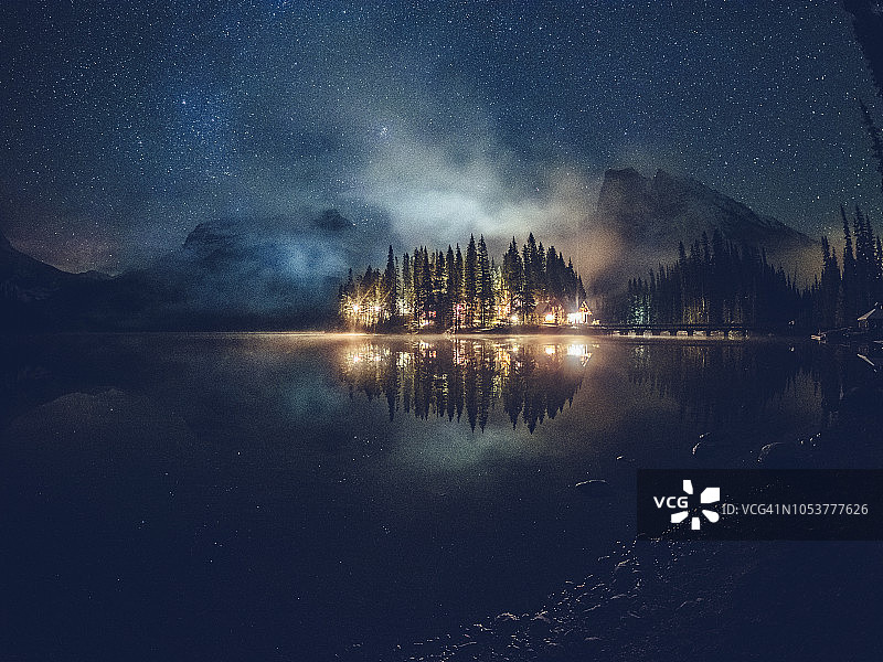 银河下小屋照明的祖母绿湖图片素材