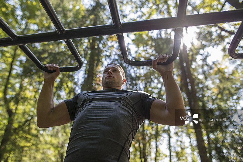 在公园里做引体向上的年轻人图片素材