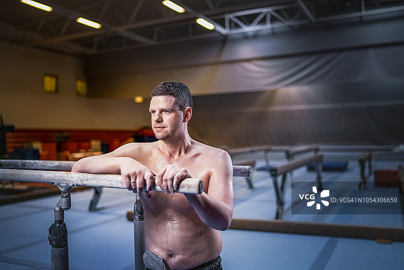 带着造口袋的男运动员靠在健身房的双杠上图片素材