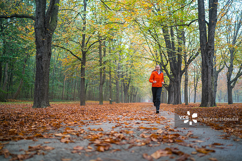 女人独自在秋日大道上慢跑图片素材