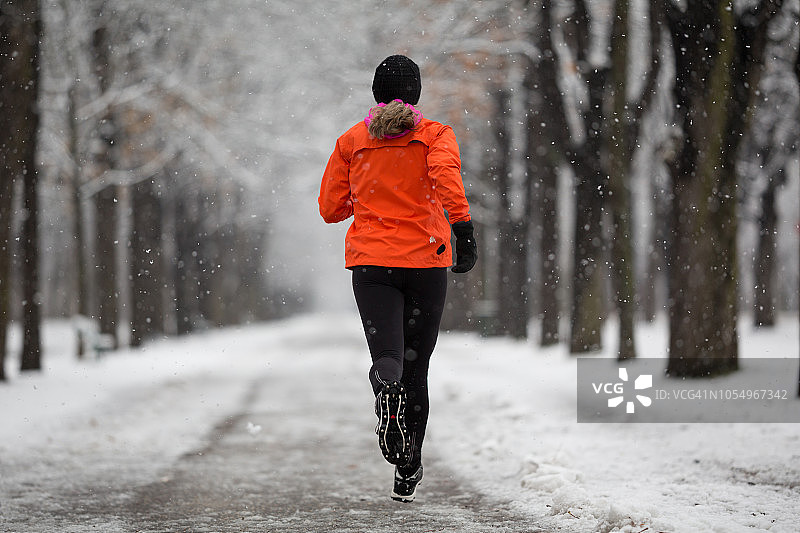 在雪天道路上独自慢跑的女子的背影图片素材