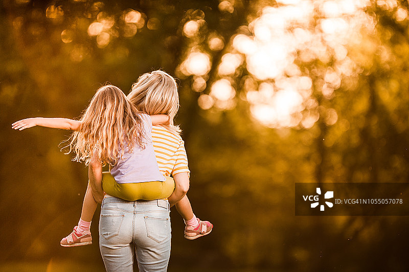 母亲和女儿在户外嬉戏的背影图片素材