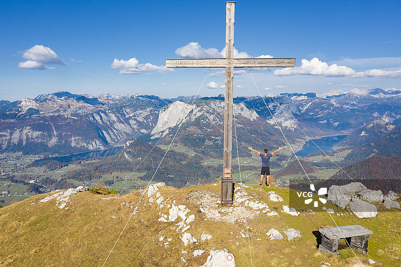 男子站在钦肯峰顶十字架旁，俯瞰奥地利的巴德奥塞图片素材