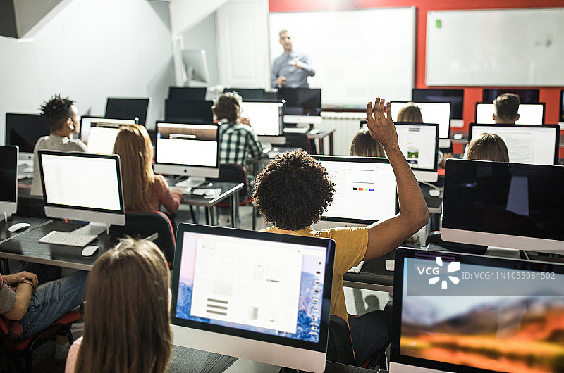 在电脑室上课时举手的学生的背影图片素材
