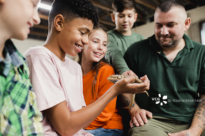 少年抱着一只鬃狮蜥图片素材