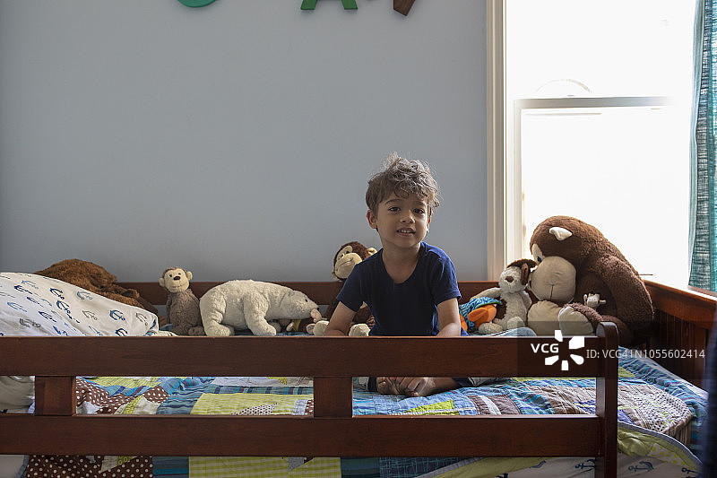 坐在床上的小拉美裔男孩图片素材