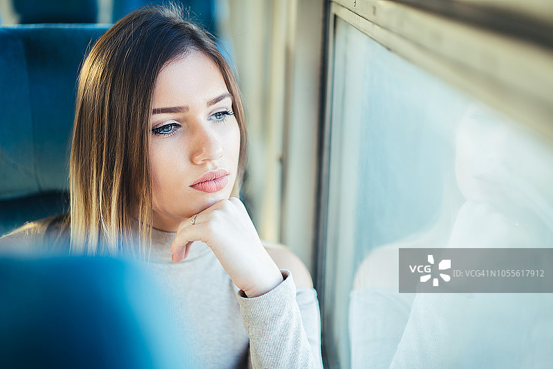 乘火车旅行的年轻旅行者，坐在靠窗的地方。图片素材