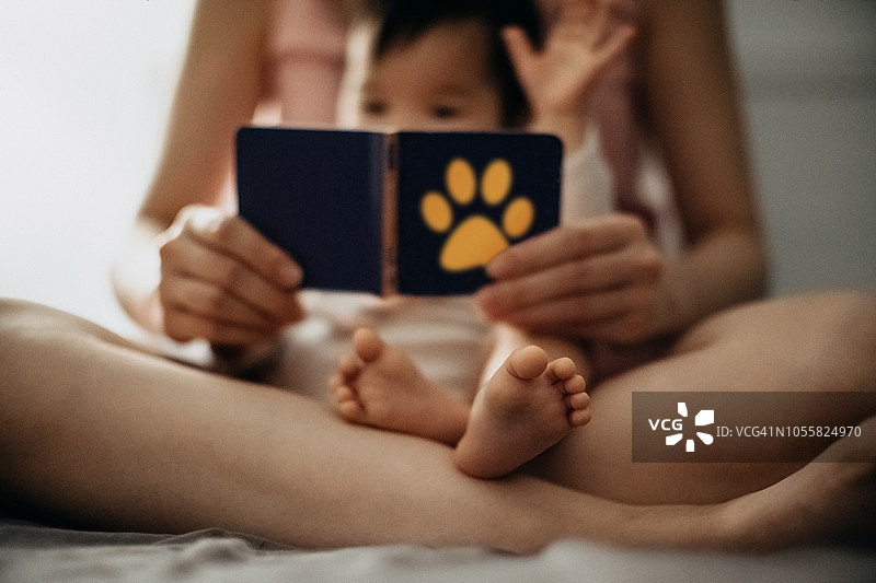 睡前，女婴坐在妈妈的腿上一起看书图片素材