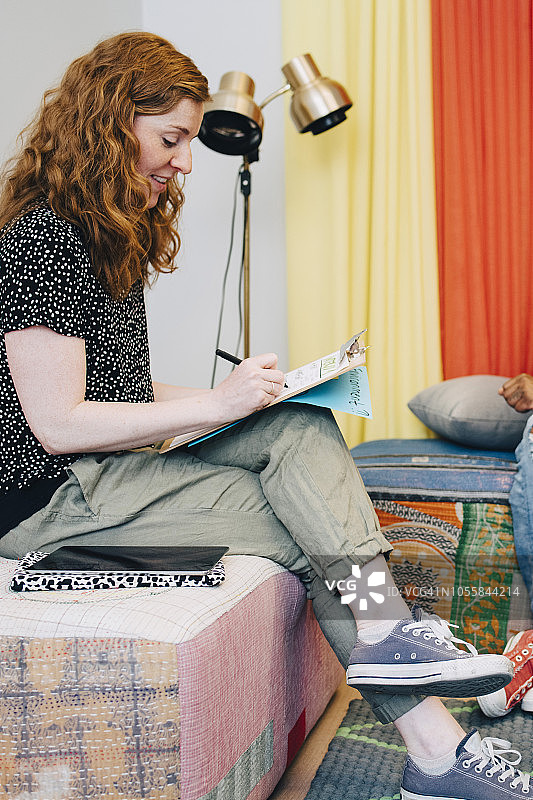 红发女商人坐在创意办公室大厅里，在剪贴板上书写图片素材