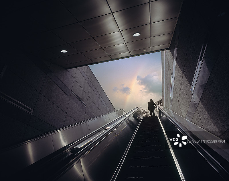 乘坐自动扶梯走向彩虹天空的商务人士图片素材