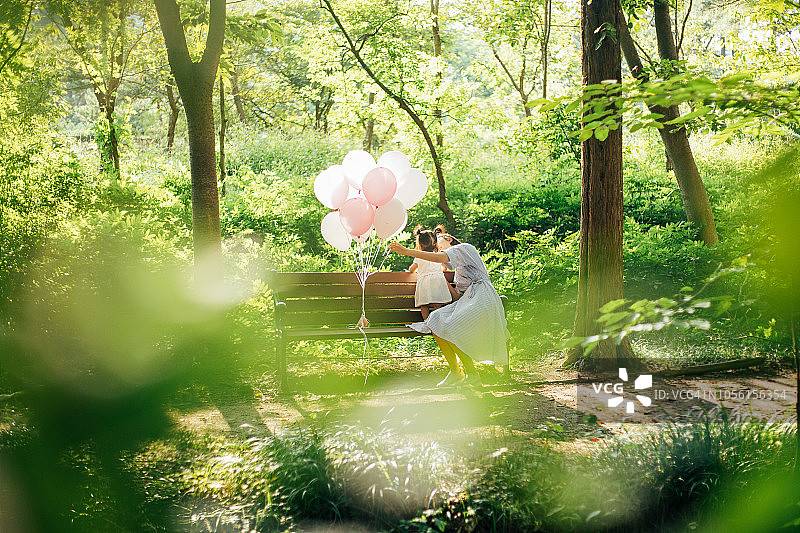 年轻妈妈和女婴坐在长椅上放松图片素材