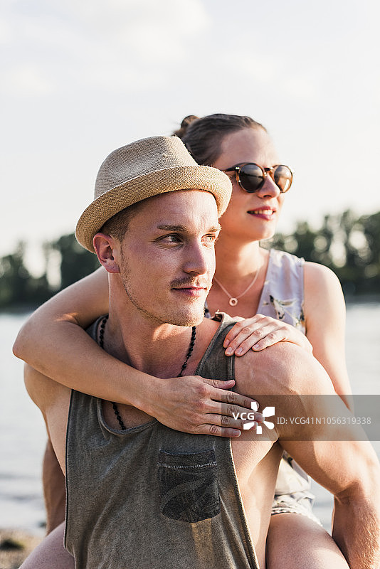 年轻男人在河岸边背着女友图片素材