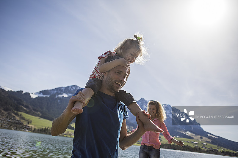 奥地利蒂罗尔州瓦尔希湖：快乐的父亲扛着女儿在湖边图片素材