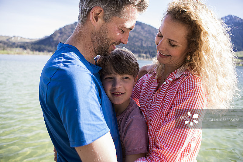 奥地利蒂罗尔州瓦尔希湖：幸福的父母与儿子在湖边亲密依偎图片素材