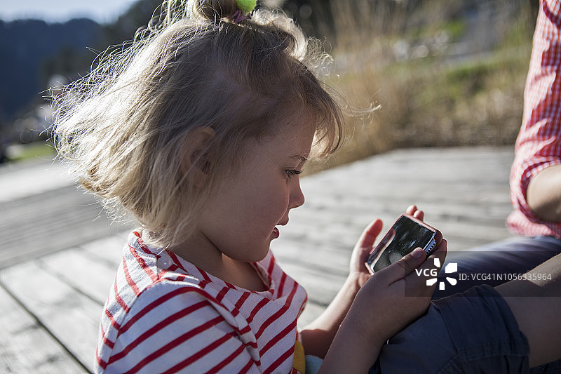 在码头上拿着母亲手机的女孩图片素材