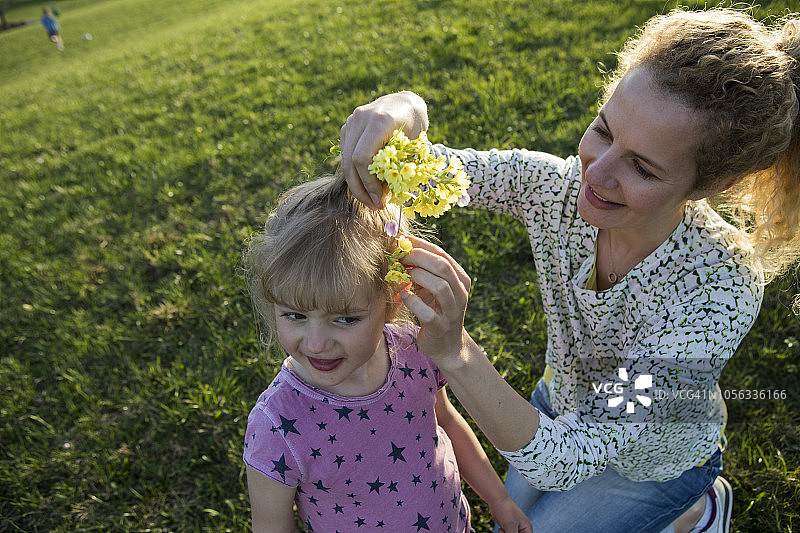 奥地利蒂罗尔州瓦尔希湖，母亲在高山草甸上给女儿的头发戴上鲜花图片素材