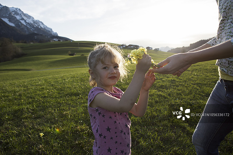 奥地利蒂罗尔州瓦尔赫湖：女孩和母亲在阿尔卑斯草甸上手持鲜花的肖像图片素材