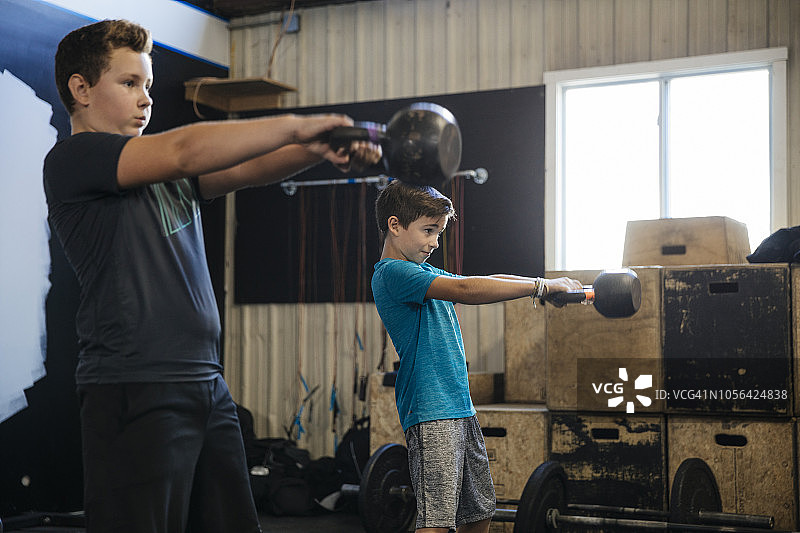 男孩在健身房举壶铃图片素材