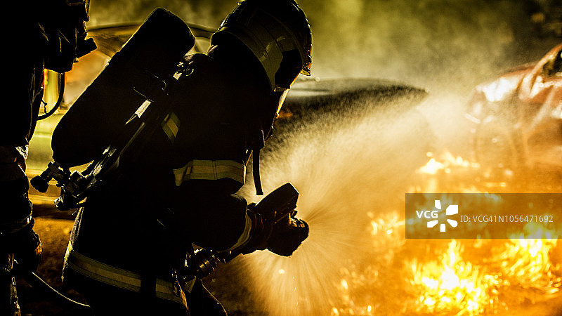 两名消防员正在扑灭燃烧的车辆图片素材