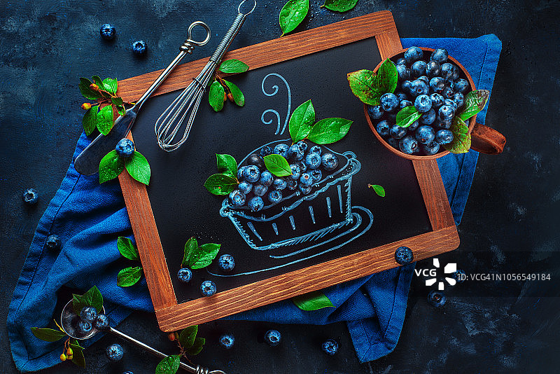 蓝莓派糕点食谱概念。真正的浆果和粉笔画组合。创意美食摄影，上方有复制空间。图片素材