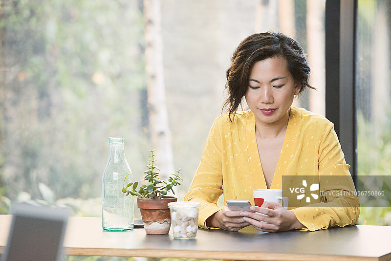 在咖啡馆用手机发短信的中国女人图片素材