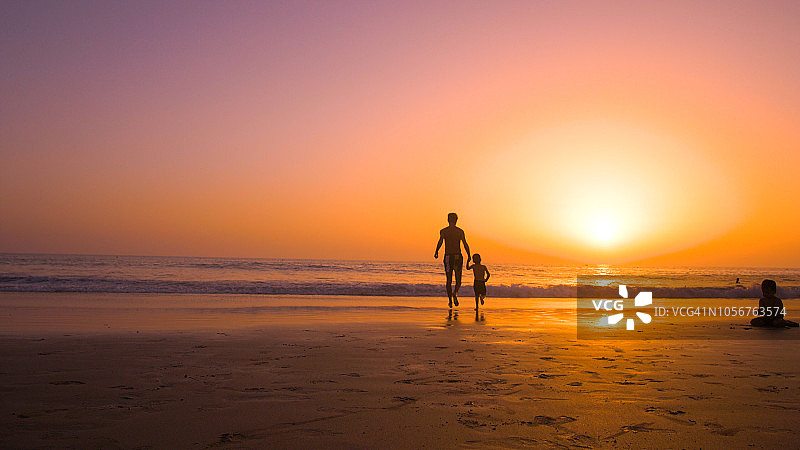 日落时分，父亲和两个孩子在海滩的剪影图片素材