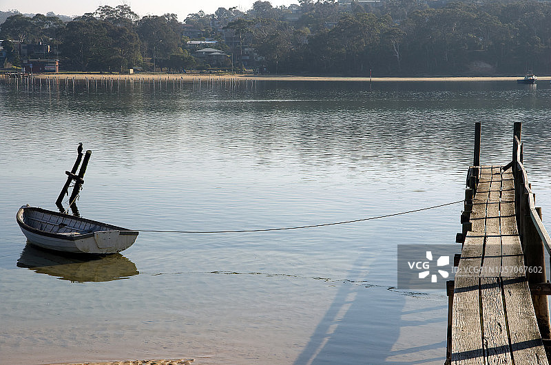 系泊在澳大利亚新南威尔士州梅里布拉沼泽溪简易木制码头上的划艇图片素材