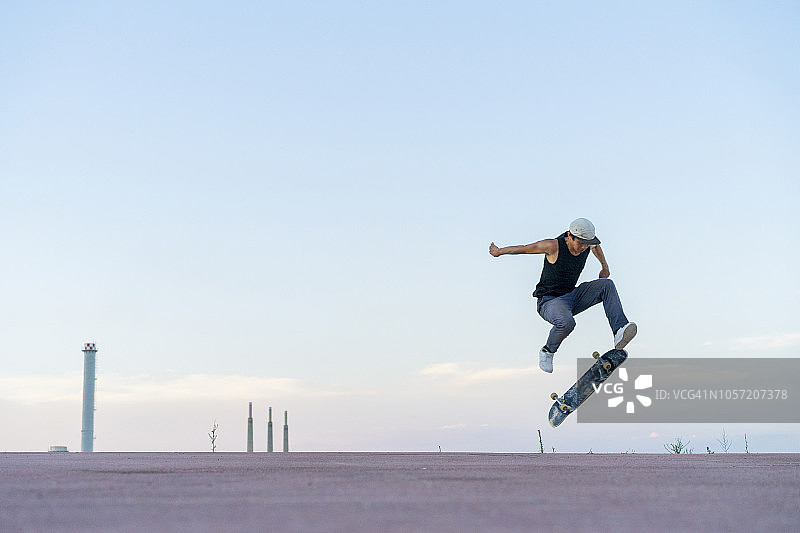 年轻人在黄昏时分的巷子里玩滑板图片素材