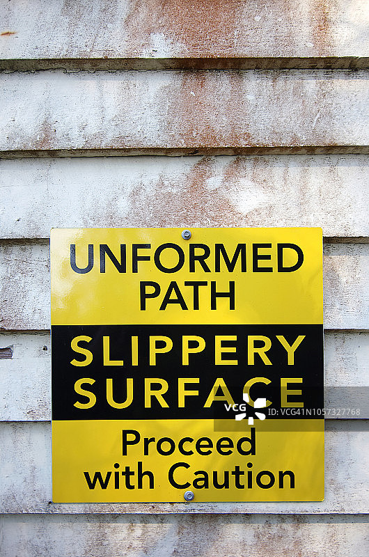 船棚木墙上的“未成形的小路。路滑。小心通行”标志图片素材