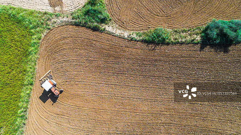 红色土壤中拖拉机耕地的鸟瞰图图片素材