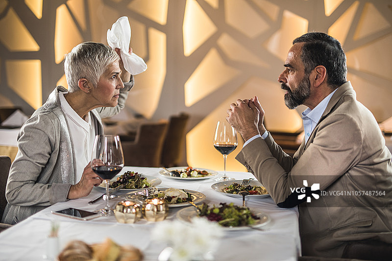 一对沮丧的中年夫妇在餐厅的晚餐上争吵图片素材