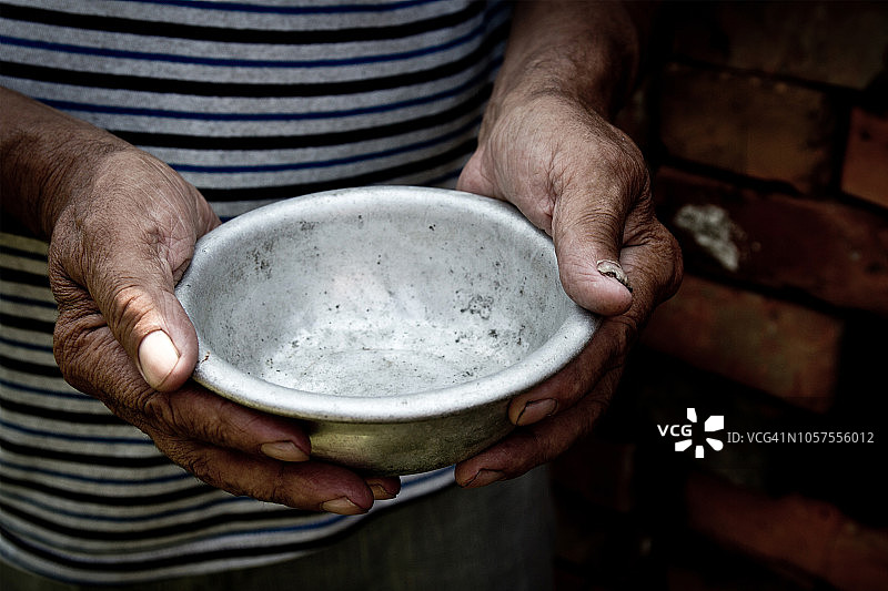 一位贫困老人的手拿着一个空碗，饥饿或贫困的概念，选择性聚焦，退休后的贫困，无家可归，施舍图片素材