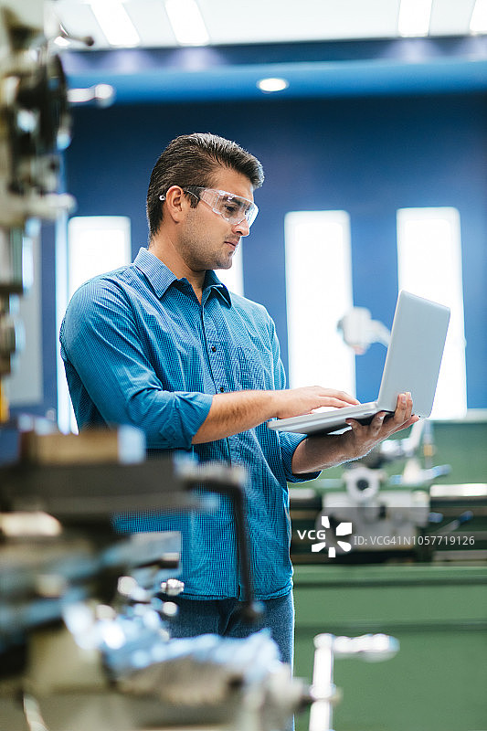 在商店里专注于笔记本电脑的拉丁裔工程师图片素材