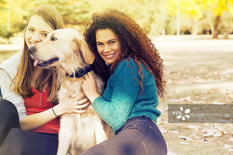 两个女孩在公园里和狗一起放松图片素材