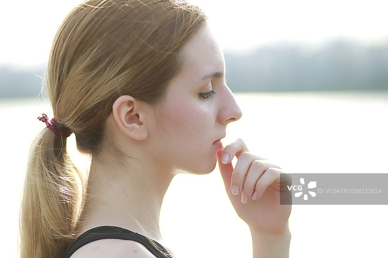 沉思的女人手托下巴在河边图片素材