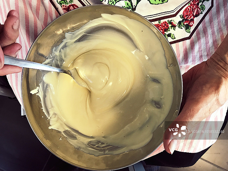 残疾老妇人在碗里搅拌融化的白巧克力图片素材