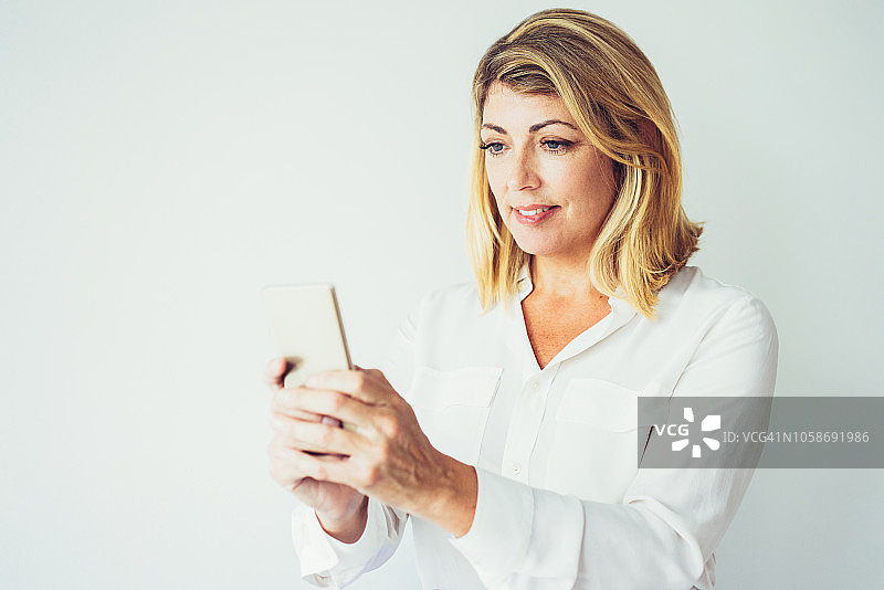 用智能手机发短信的快乐中年妇女图片素材