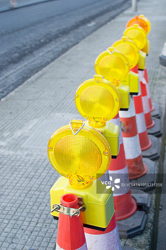 沥青路上的一排反光黄色橙色交通锥图片素材