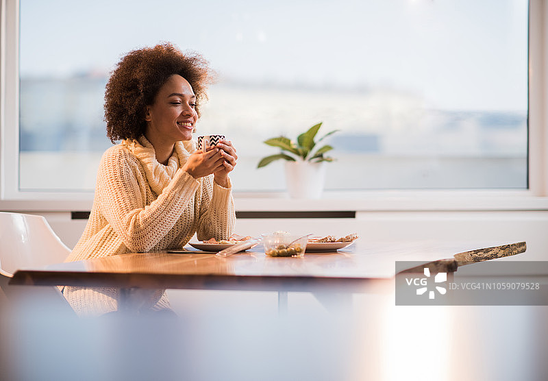 在家吃早餐时，手拿咖啡杯，做白日梦的漂亮黑人女性图片素材