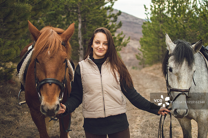 女孩牵着两匹马行走图片素材