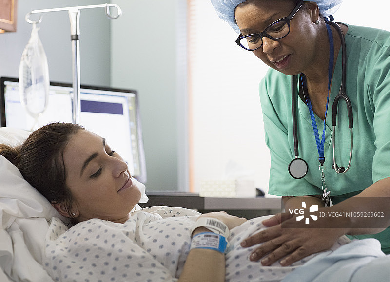 混血医生检查孕妇的腹部图片素材