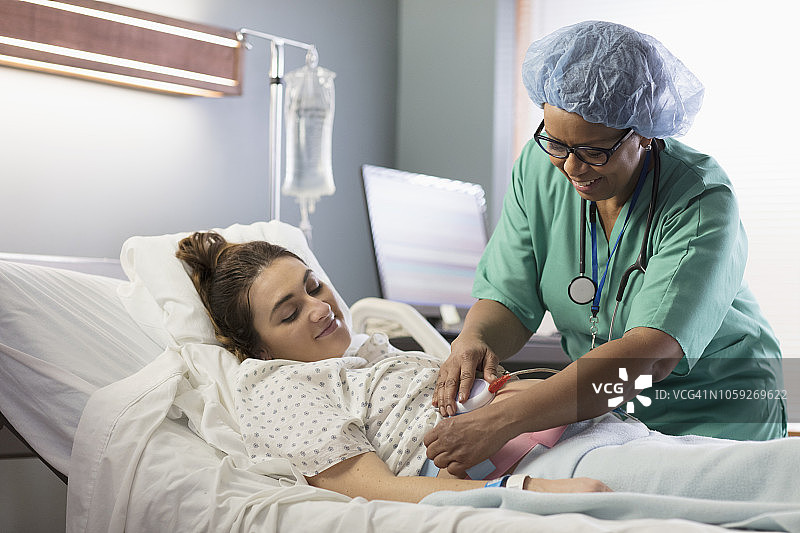 混血医生在孕妇腹部放置医院监护仪图片素材