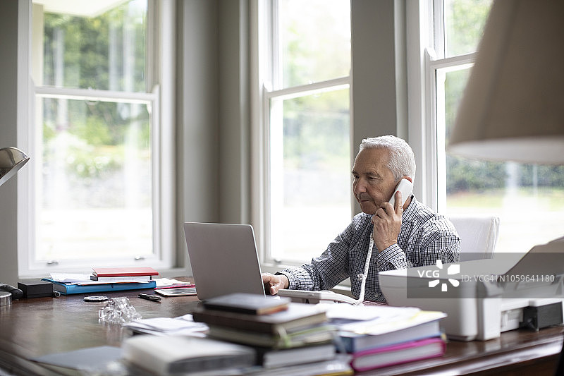 用笔记本电脑上网时打电话的男人图片素材