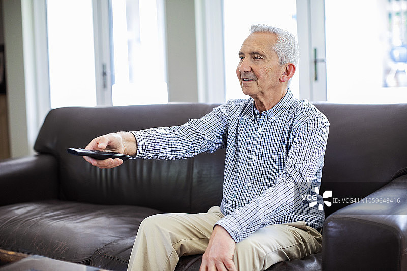 退休男子坐在沙发上看电视图片素材