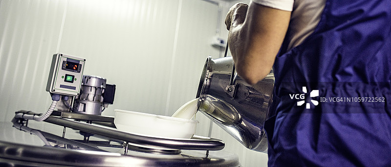 男人将牛奶倒入不锈钢工业大锅中图片素材