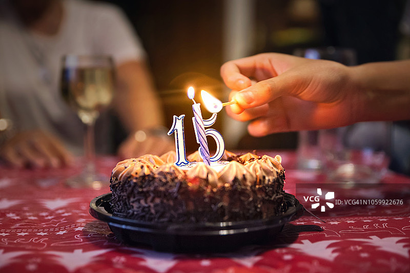 手点燃巧克力奶油生日蛋糕蜡烛特写图片素材