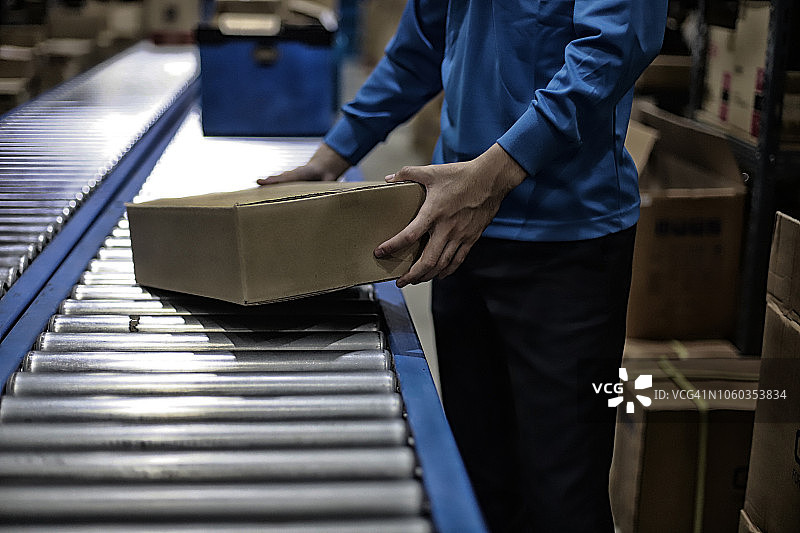仓库工人手拿传送带上的包裹图片素材