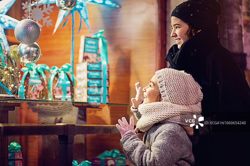 圣诞节时两个女孩在看糖果店的橱窗图片素材