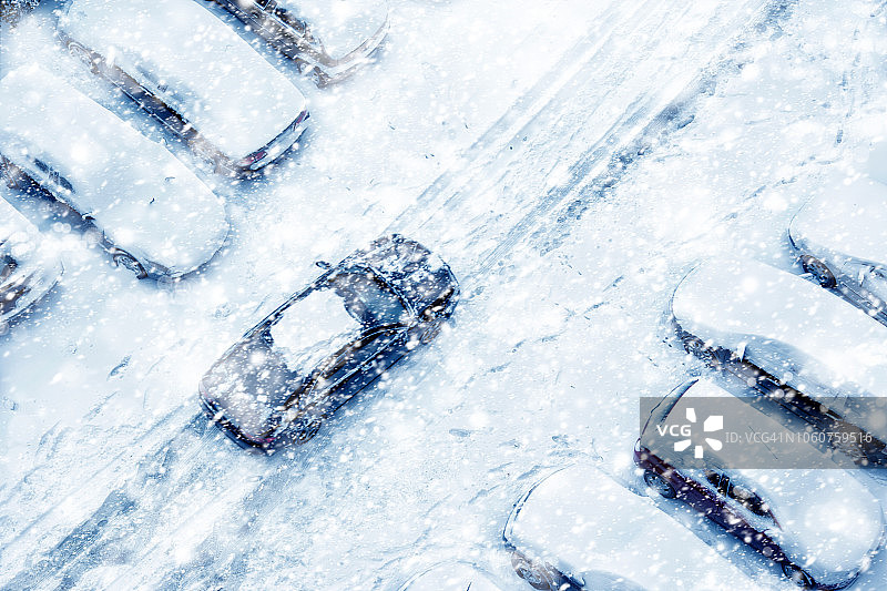 下雪期间覆盖着积雪的城市街道和停放的汽车的鸟瞰图图片素材
